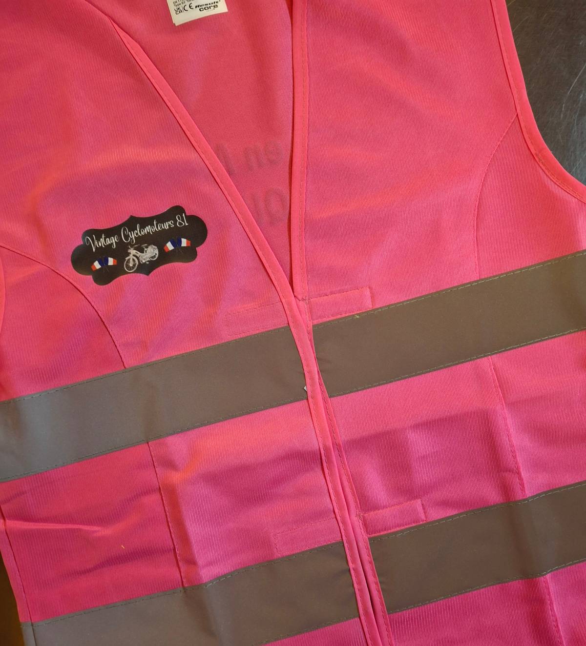 Marquage au coeur opposé d'un logo en quadrichromie sur un gilet de sécurité coupe femme rose fluo